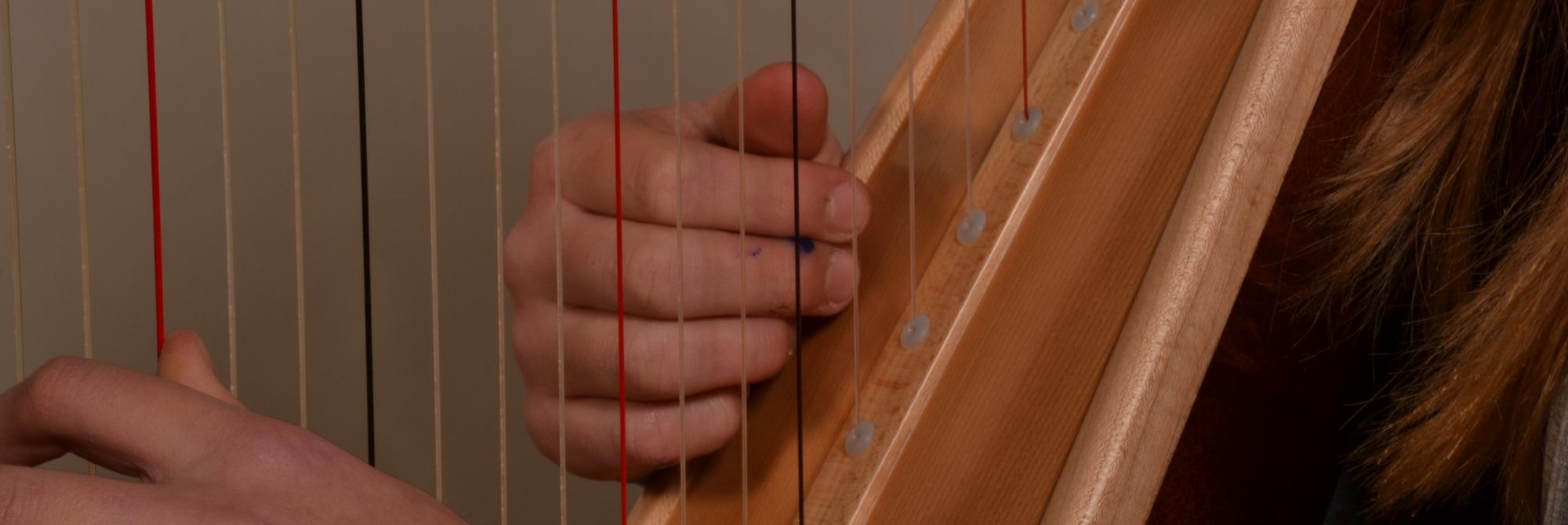 Detail van leerling die harp speelt